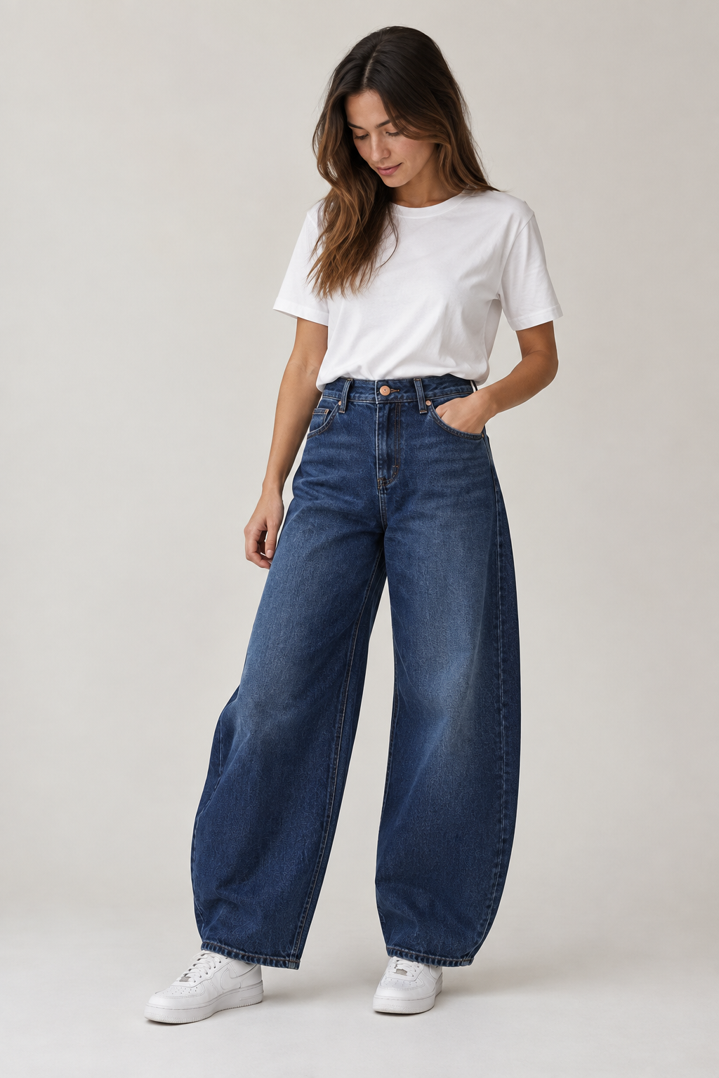 Modella indossa jeans Teresa C. Casual Chic Lab a gamba larga blu scuro a vita alta con t-shirt bianca e sneakers